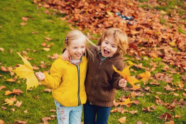 Tatlı kız ve erkek, sonbahar parkında yürüyen küçük bir çift. Çocuk dostluğu ve nezaketi. Çocuklar sever.