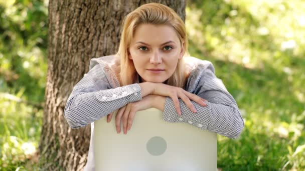 Étudiante en plein air, jeune femme assise sur une herbe dans un parc avec ordinateur portable et sourires. — Video