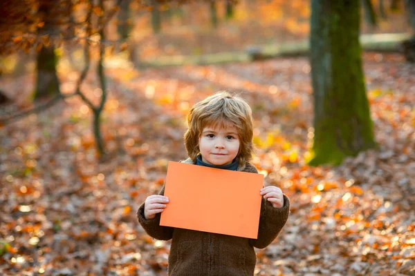 Autumn. Child holding advertising board, blank board advertising, ads, messages, empty paper sheet. Seasons sale. Discount. Black friday. Marketing. Banner copy space for text.