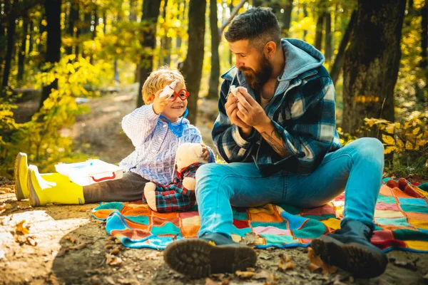 Çocuk sonbahar parkında soğuk algınlığına çare bulur. Baba ve oğul sonbahar ormanında oynuyorlar. Baba ve oğul sonbahar parkında gülüyorlar.. — Stok fotoğraf