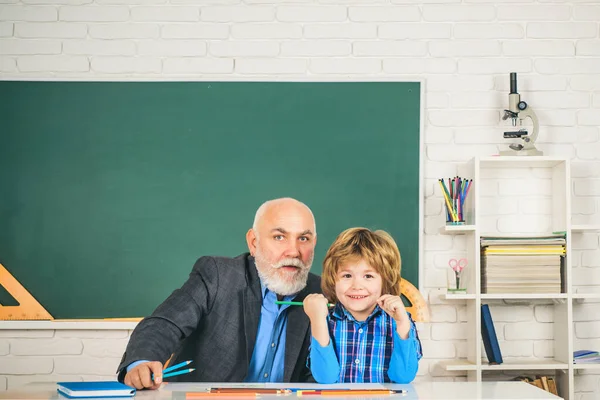 Nonno e figlio si divertono insieme. Buon nipote e nonno seduti a una scrivania al chiuso. Torniamo a scuola. Concetto di apprendimento e istruzione. — Foto Stock