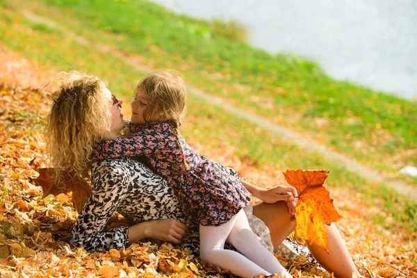 Mãe abraçando com sua filha ao ar livre na natureza outono no dia ensolarado. Mãe e criança abraçando e sorrindo. — Fotografia de Stock