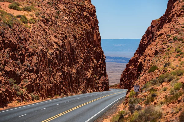 道路の旅。道路の高い赤い岩に対して。不毛の風景、エンドレスストレート. — ストック写真