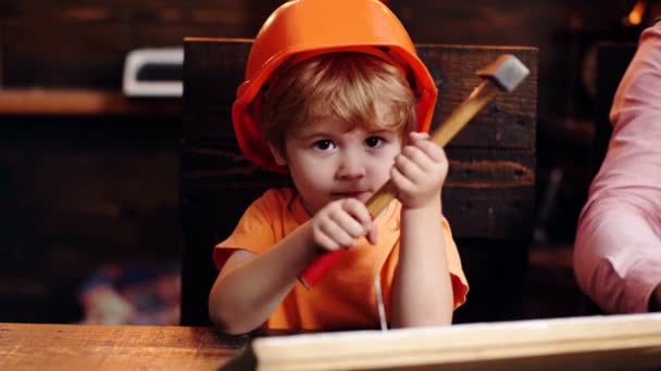 Kind mit Helm verstopft den Nagel. Kid Builder Konzept. Ausbildung zum kreativen Ingenieur - Junge in der Werkstatt. — Stockvideo