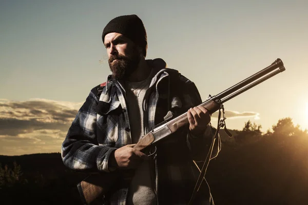 Hunter vadászpuskával az őszi erdőben. Lövész vadász a Sunseten. Vadász ősszel vadászidény. — Stock Fotó