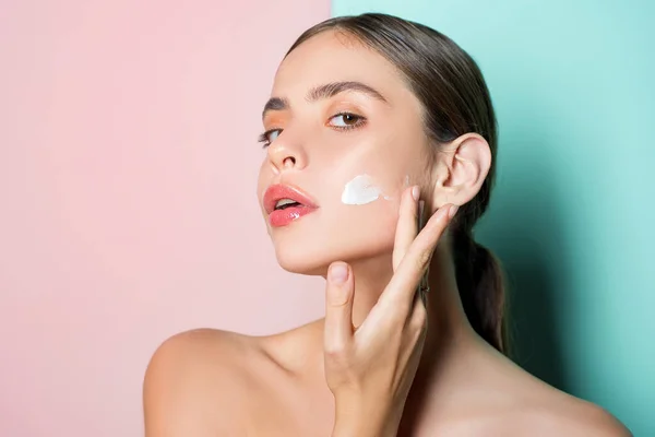 Retrato de bela jovem senhora tocando bochecha com a mão aplicando creme facial. Pura pele e conceito de beleza natural. Face care conceito facial. — Fotografia de Stock