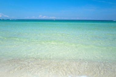 Tropikal sahildeki sakin deniz sahilinin üzerinde mavi gökyüzü olan bulutlar. Mavi deniz tasarımı için pankart veya duvar kağıdı, okyanus dokusu veya desen, yaz arkaplanı.