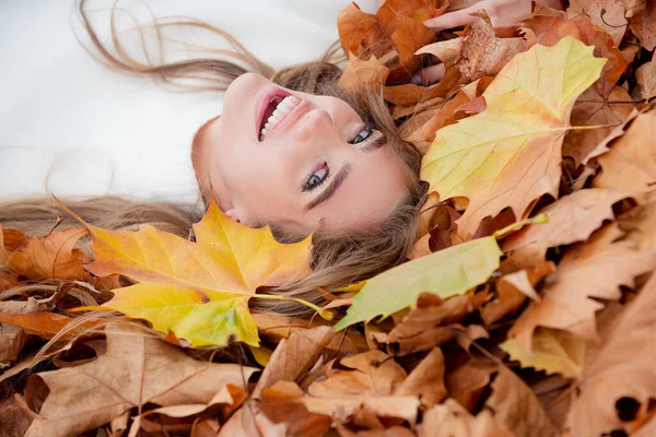 Mulher deitada em folhas de outono. Close-up retrato de mulher bonita ao ar livre. — Fotografia de Stock
