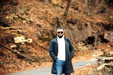 Sonbahar arka planında yakışıklı genç bir adam kameraya bakıyor..