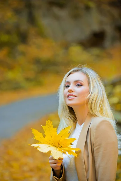 Tendência de moda outono. Jovem mulher bonita andando no parque segurando folha. Folhas caindo, tempo de queda na natureza. — Fotografia de Stock