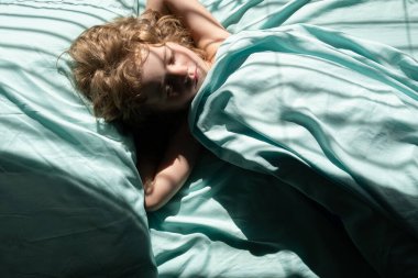 Kafkasyalı çocuk sabahları yatakta battaniyenin altında yastıkta uyuyor..