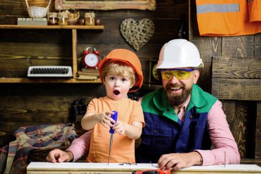 Marangoz aletleri. Baba oğul başlık takıp tornavida kullanmayı öğrenmekle meşguller..