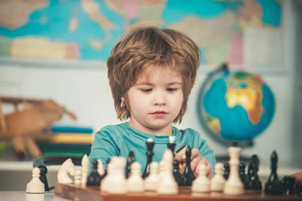 Geconcentreerd jongetje zit aan tafel en schaakt. Jongen kind schaken thuis. — Stockfoto