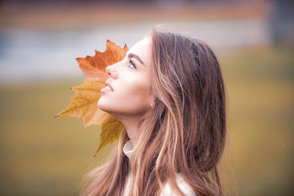 Cara de otoño de moda de mujer hermosa con hoja. Belleza chica al aire libre disfrutando de la naturaleza. — Foto de Stock