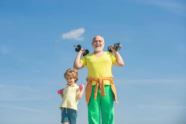 Nagyapa és unoka súlyzókkal a kezükben. A sportolás ingyenes. Egészséges családi életmód. Atlétikai család súlyzókkal. Mint a sport.. — Stock Fotó