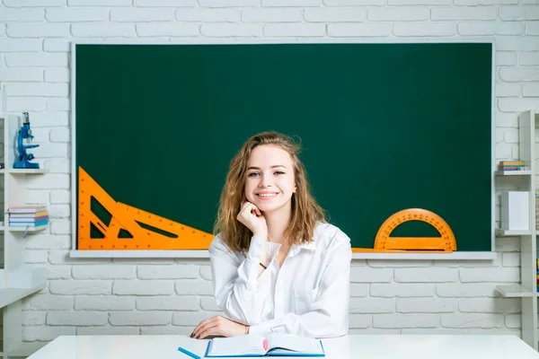Teenage student in uniform on blackboard background.