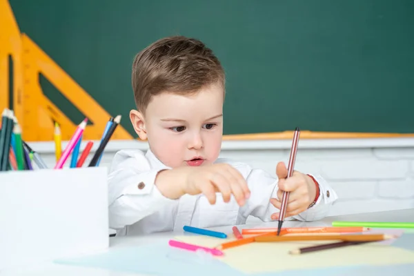 教室で書く子供の少年。家庭での授業中に宿題を勉強する少年. — ストック写真