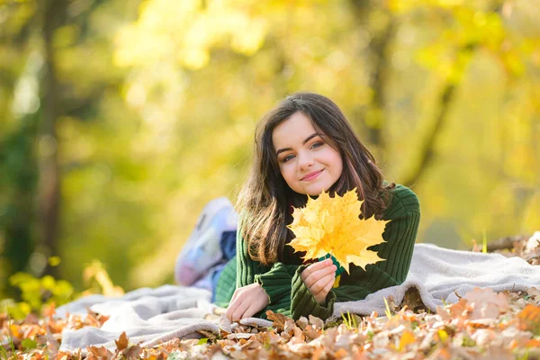 Adolescente outono alegre com cabelo longo e saudável segurando folha de bordo amarelo ao ar livre no dia ensolarado. Adolescente bonita no parque de outono. — Fotografia de Stock