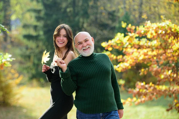 Nieta con abuelo anciano de pie al aire libre en el parque de otoño. Cuidar a la hija adulta pasar tiempo con el viejo papá. —  Fotos de Stock