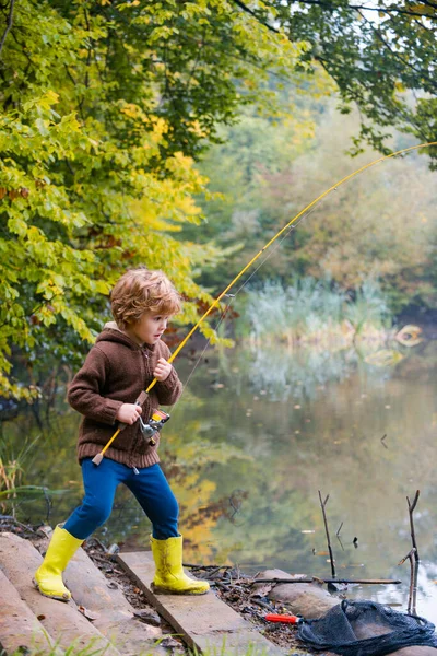 Liten pojke som fiskar. Grabben drar spö när du fiskar på helgen. — Stockfoto