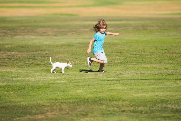 Criança feliz correr com um cão ao ar livre. — Fotografia de Stock