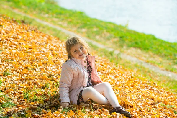 Hojas cayendo. Niño sonriente sobre fondo natural de otoño. Jugando en el parque de otoño. — Foto de Stock