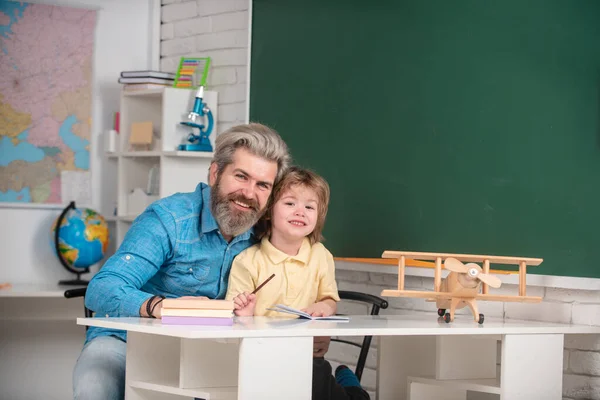 Padre che insegna al figlio. Bambino divertente con il padre che si diverte sullo sfondo della lavagna. Tutoraggio post-scolastico. Insegnante a casa o tutor per i compiti. Contesto dell'istruzione. — Foto Stock