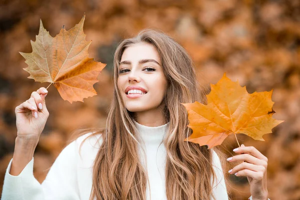 Lächelnde Frau mit Herbstblättern. Mädchen mit orangen Blättern. Saison und Herbstferien. Schönheit und Mode. Lächelndes Model mit stylischem Haar. — Stockfoto