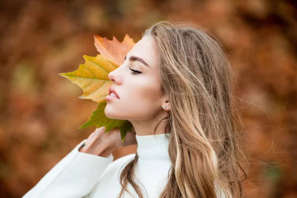 Portrait de jeune femme joyeuse avec des feuilles d'automne devant le feuillage. — Photo