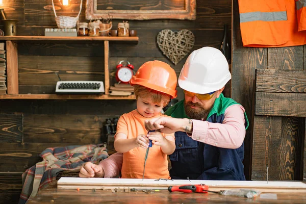 Vader en zoon aan het repareren in de werkplaats. Kind met timmermansgereedschap in houtwerk. — Stockfoto