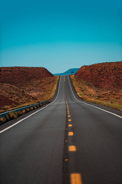 Asphalt road straight through the field with blue sky in autumn. Asphalt texture, way background.