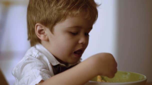 Grappig kind eet pap met melk. Klein ventje geniet van zijn pap — Stockvideo