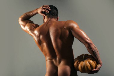 Cadılar Bayramı. Balkabaklı ve seksi kalçalı bir adam. Kaslı sırt ve genç adamın seksi gövdesi..