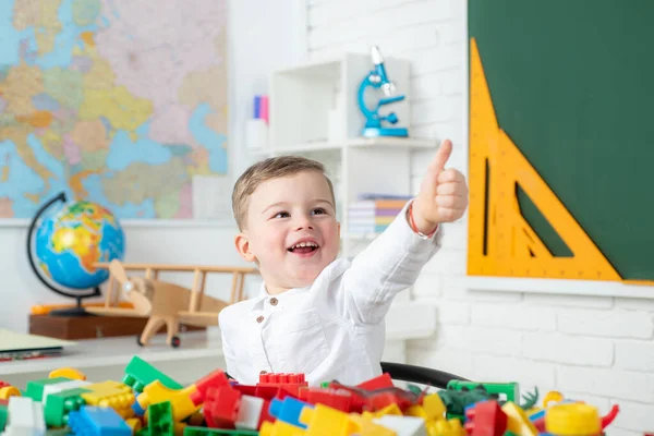Izgatott iskolás fiú feltartott hüvelykujjal. Általános iskolás gyerekek az óvodában.. — Stock Fotó