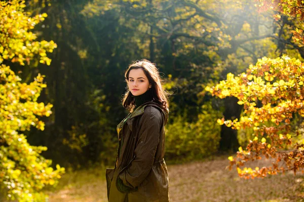 Krásná puberťačka v podzimním parku. Veselý podzim teen s dlouhými zdravými vlasy drží žlutý javorový list venku ve slunečný den. — Stock fotografie