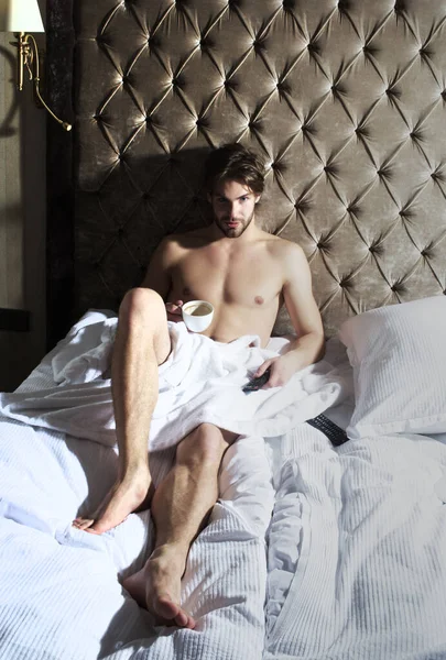 Sleeping man in bedroom. Naked muscular man having breakfast in bedroom. Sexy man drinking coffee.