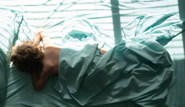 Çocuk uzanıyor ve yastığın üzerinde uyuyor. Sabah yatak odasında rahat bir şekilde uyuyan çocukların en iyi görüntüsü..