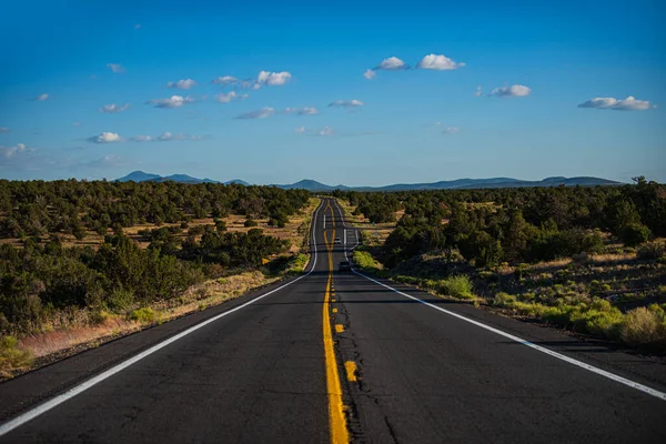 Skyline panorâmico com estrada vazia. Paisagem com rochas, céu ensolarado com nuvens e estrada de asfalto à noite no verão. — Fotografia de Stock