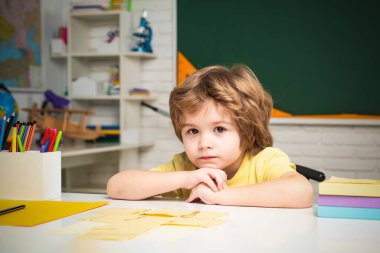 Karatahta masasının yanındaki sınıfta tatlı bir çocuk. İlkokuldan çocuklar.