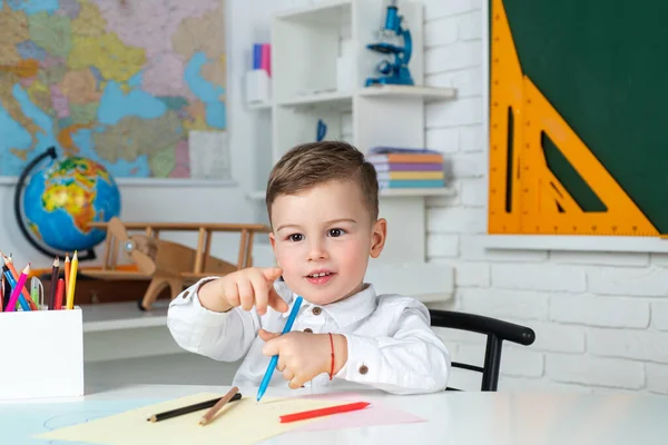 Der Schuljunge lernt zu Hause und macht Hausaufgaben. Kind in der Hausschule. Heimatpädagogisches Konzept. Nettes Kind sitzt drinnen am Schreibtisch. — Stockfoto