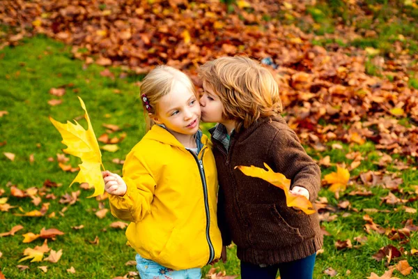 Glückliche kleine Kinder, die sich umarmen und küssen. Junge gibt seiner Schwester einen Kuss auf die Wange. — Stockfoto