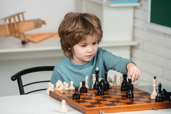 Malý chlapec hraje šachy. Žák přemýšlí o dalším tahu v šachové partii. Inteligentní děti. — Stock fotografie