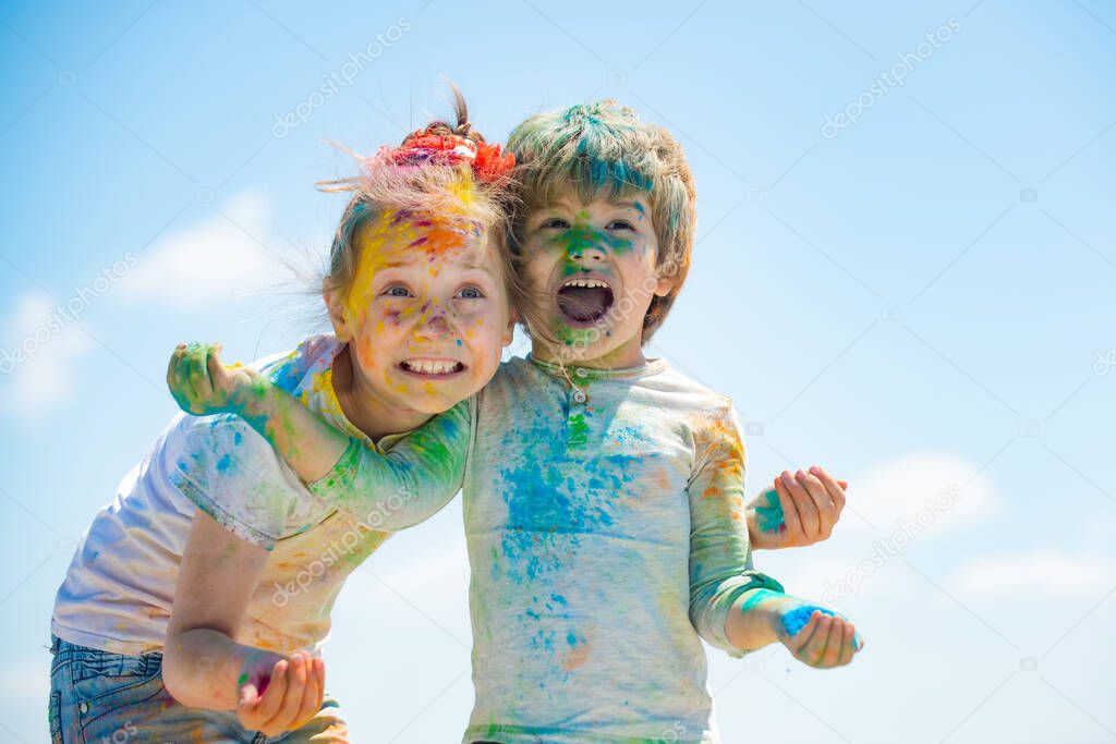 Happy kids playing with colored holi powder. Funny cute preschoolers looking at camera while embracing.