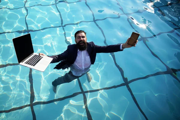 Безумный комический бизнес. Забавный бизнесмен в костюме с ноутбуком и мобильным телефоном на бассейне. — стоковое фото