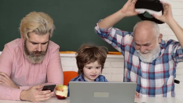 Concepto de educación tecnológica. Aprender en línea. Padre, abuelo e hijo estudian en casa y hacen los deberes escolares. Abuelo en gafas VR. — Vídeo de stock