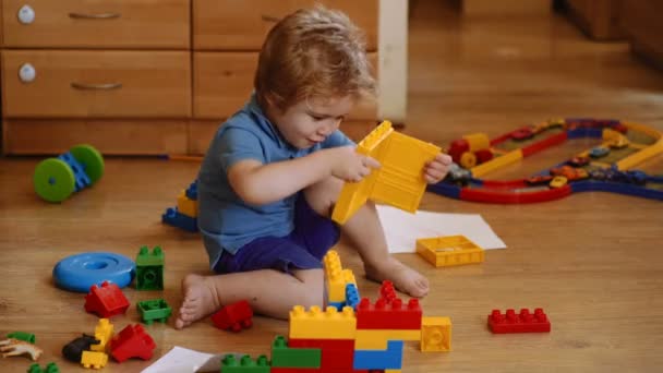 Niño jugando y construyendo con ladrillos de plástico de colores. Aprendizaje y desarrollo tempranos. Chico está jugando con la construcción de ladrillos — Vídeo de stock