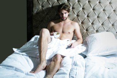 Üstsüz seksi erkek model yatak odasında tek başına yatıyor. Baştan çıkarıcı ve seksi adam..