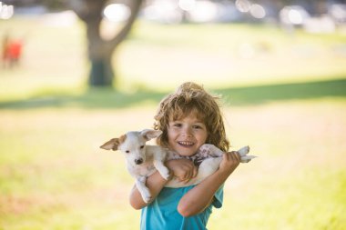 Köpekli çocuk doğada dinleniyor. Sevimli şirin çocuk evcil köpeğini kucaklıyor..