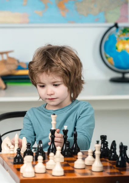 Kids chess school. Concentrated boy developing chess strategy, playing board game.