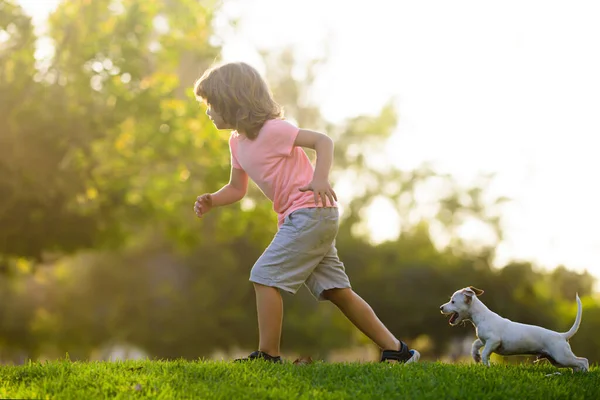 Dítě s mazlíčky štěně běží. Happy Dítě a mazlíček pes běží na zahradě. — Stock fotografie